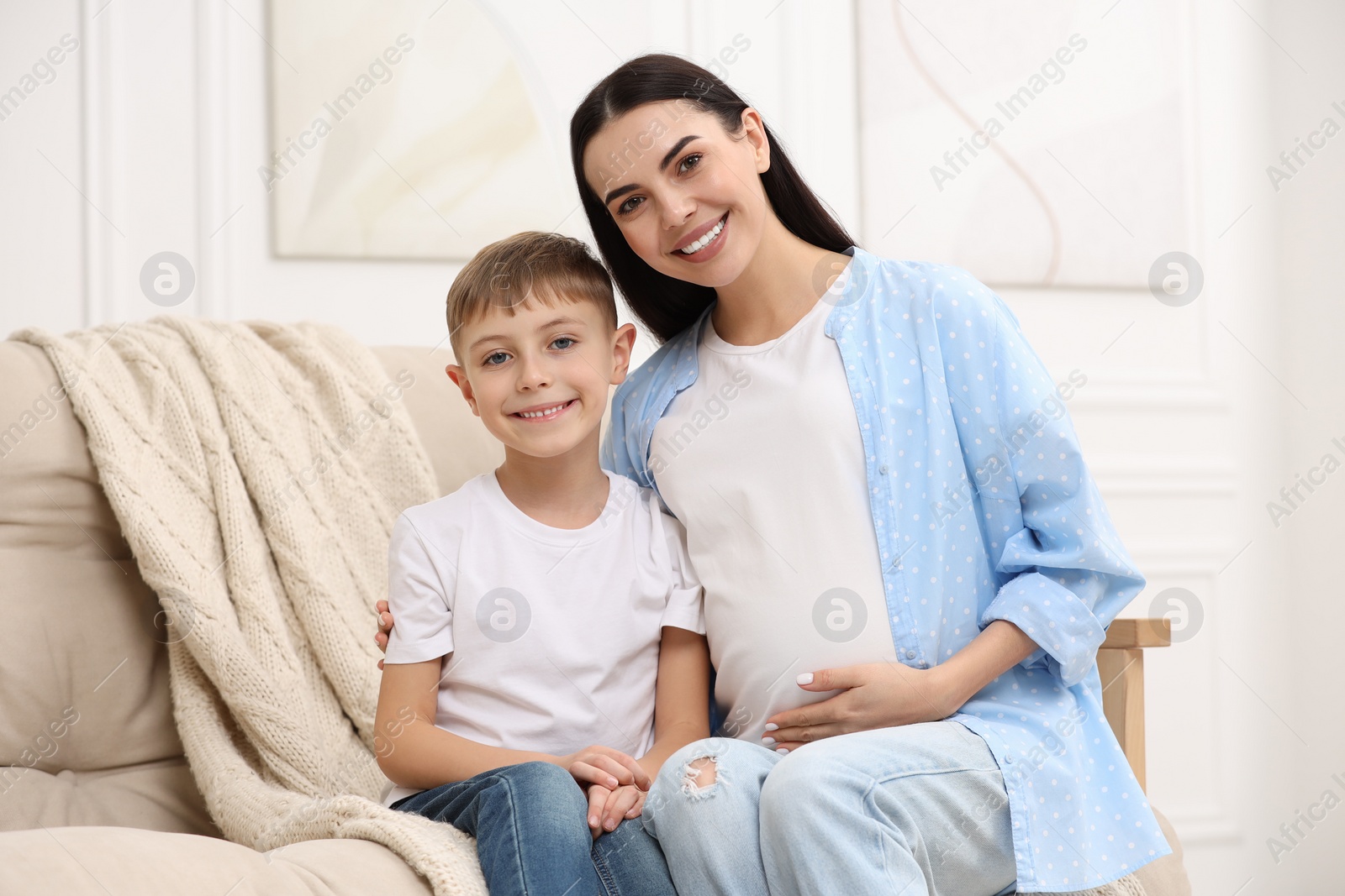 Photo of Portrait of happy pregnant woman with her son at home