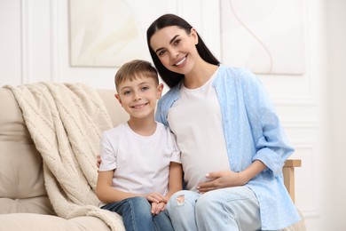 Portrait of happy pregnant woman with her son at home