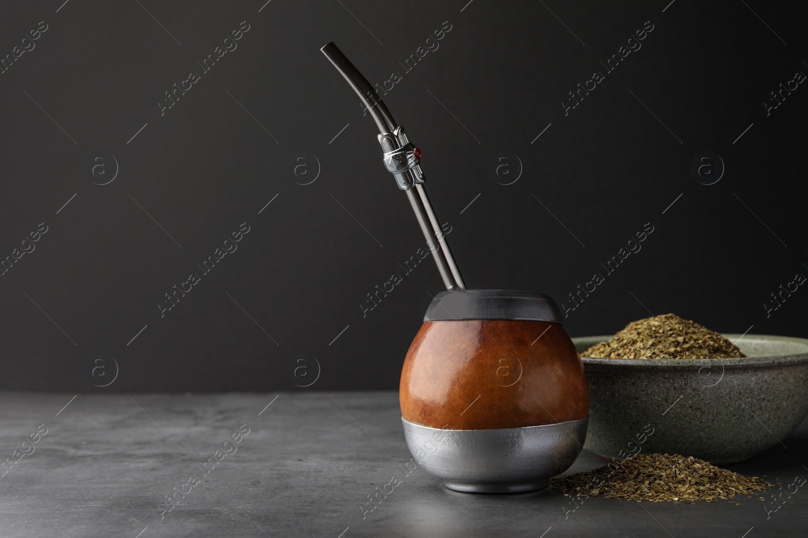 Photo of Calabash with mate tea and bombilla on light grey table. Space for text