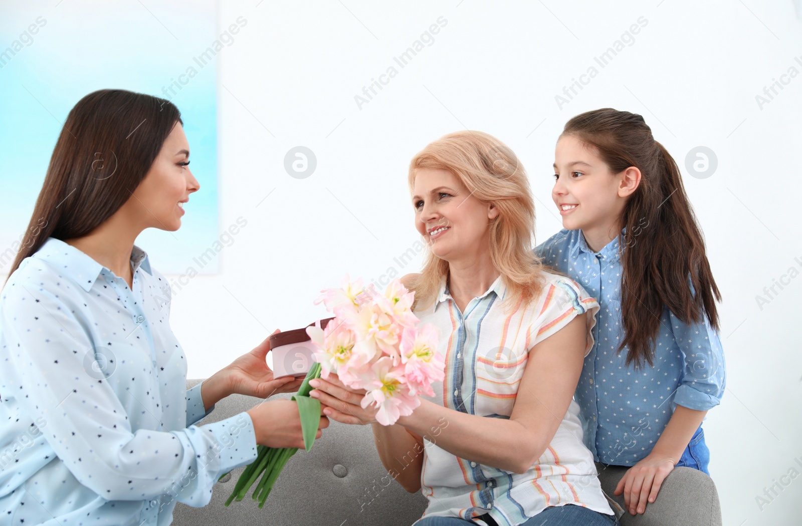 Photo of Woman and her daughter congratulating granny at home. Happy Mother's Day