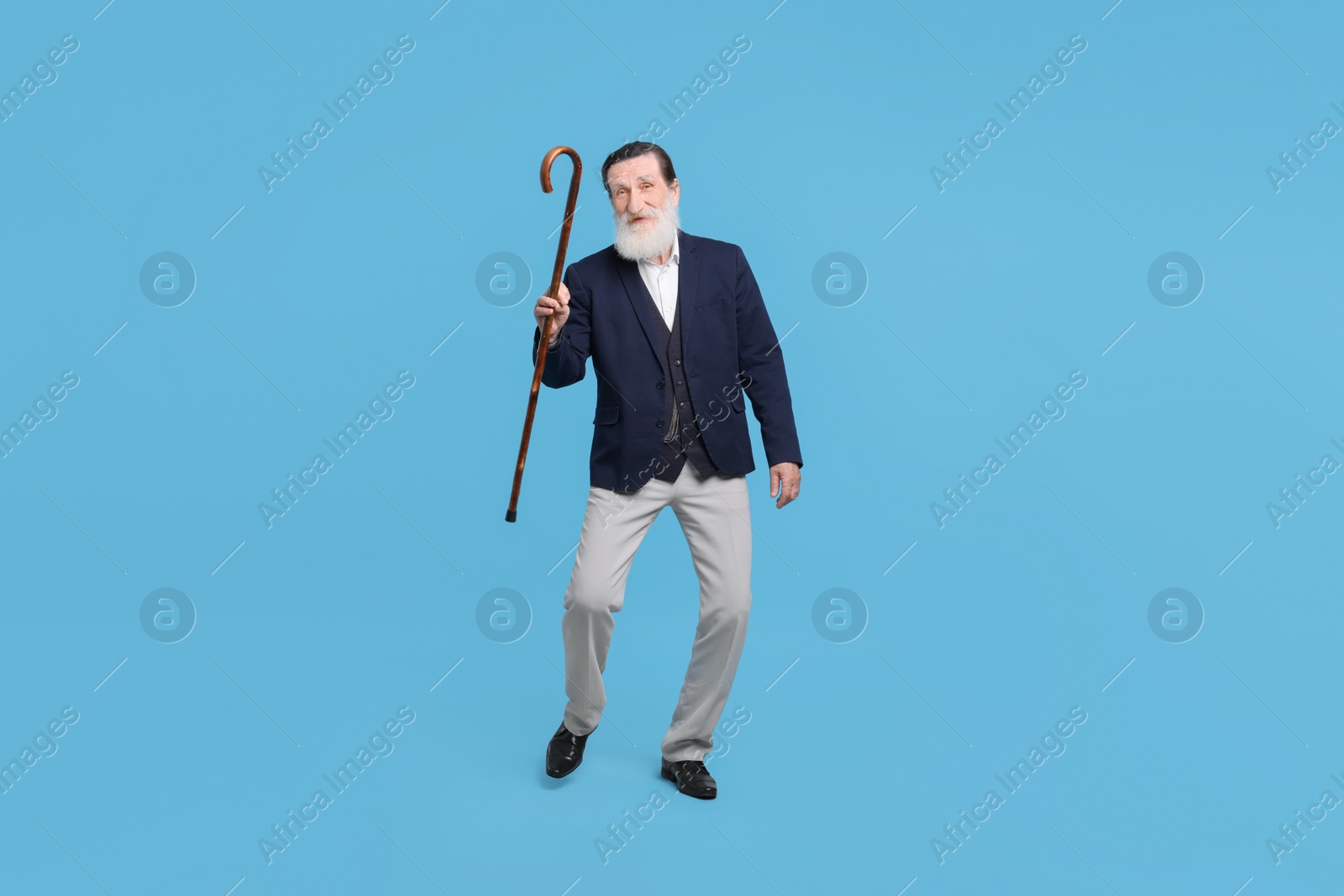 Photo of Cheerful senior man with walking cane on light blue background