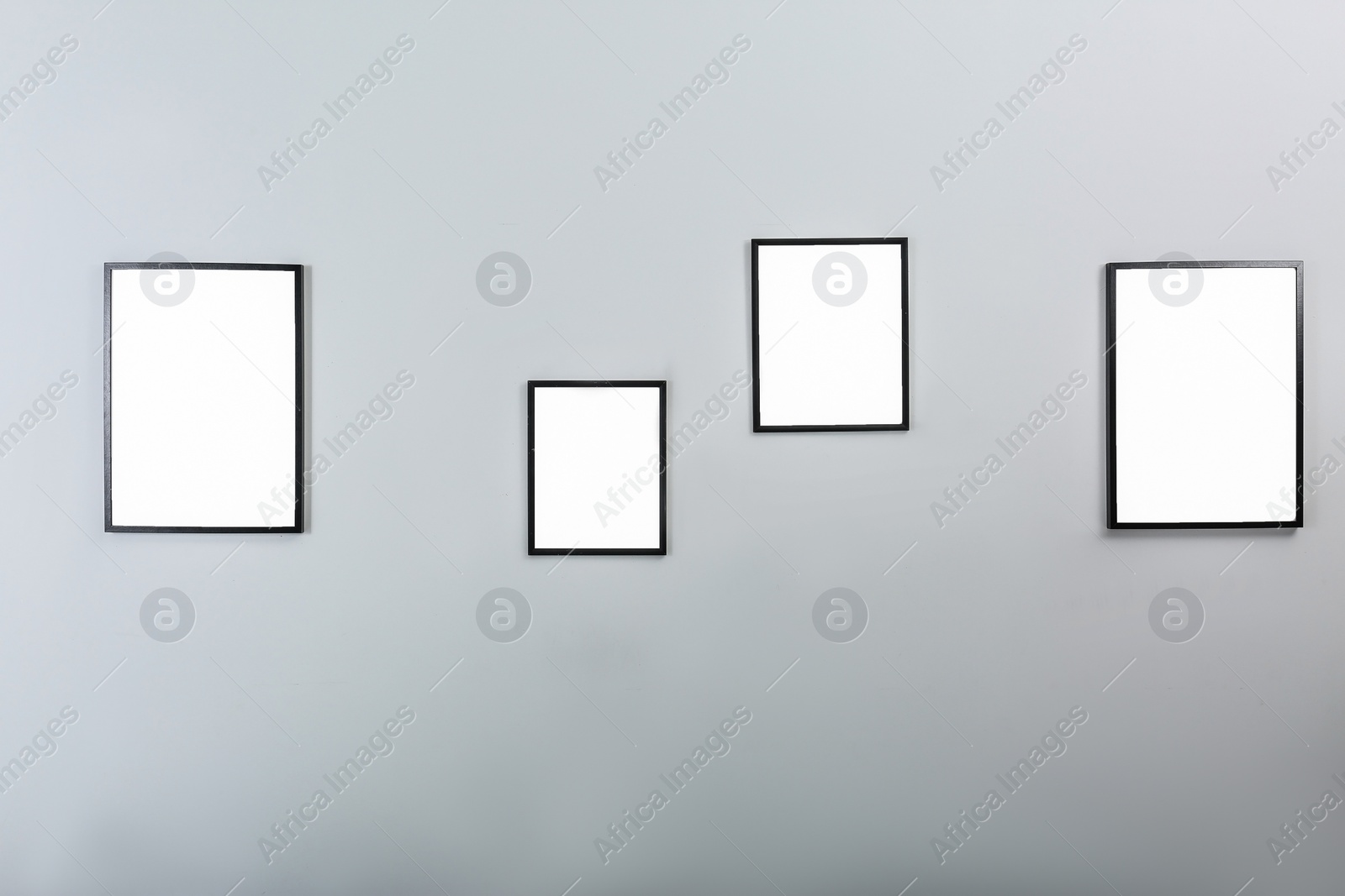 Photo of Frames with empty canvases on wall in modern art gallery. Mockup for design