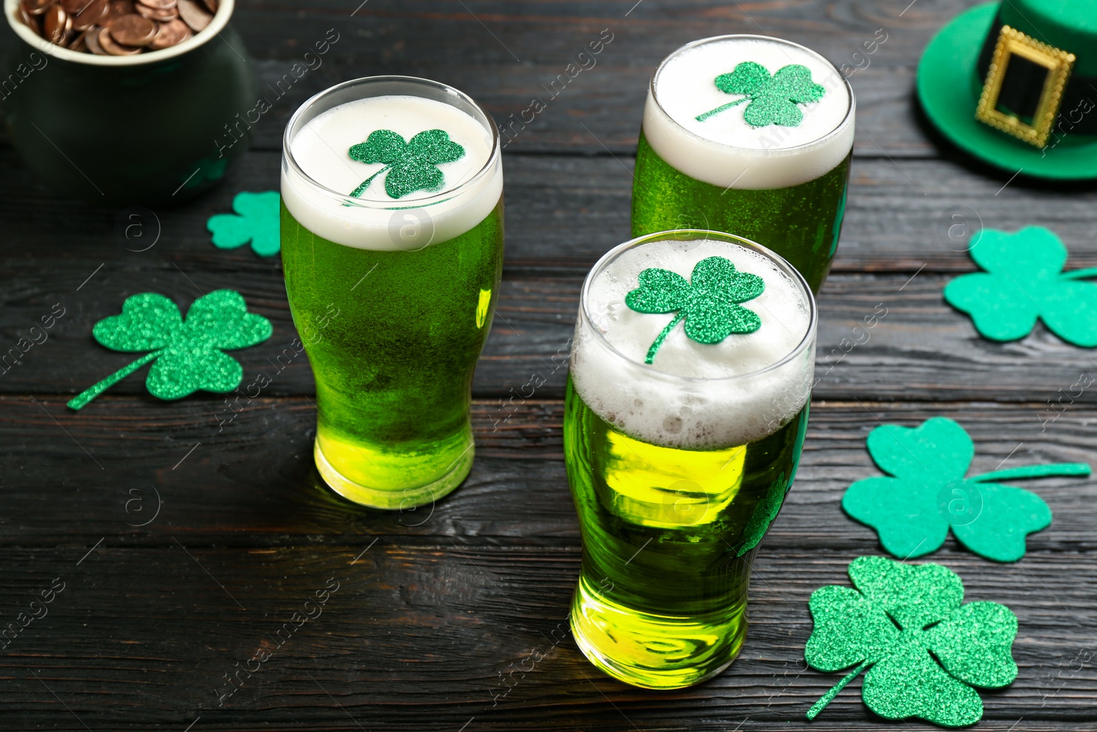 Photo of Green beer and clover leaves on black wooden table. St. Patrick's Day celebration