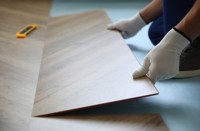 Worker installing laminated wooden floor indoors, closeup