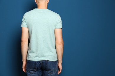 Photo of Back view of young man wearing blank t-shirt on blue background, closeup. Mockup for design