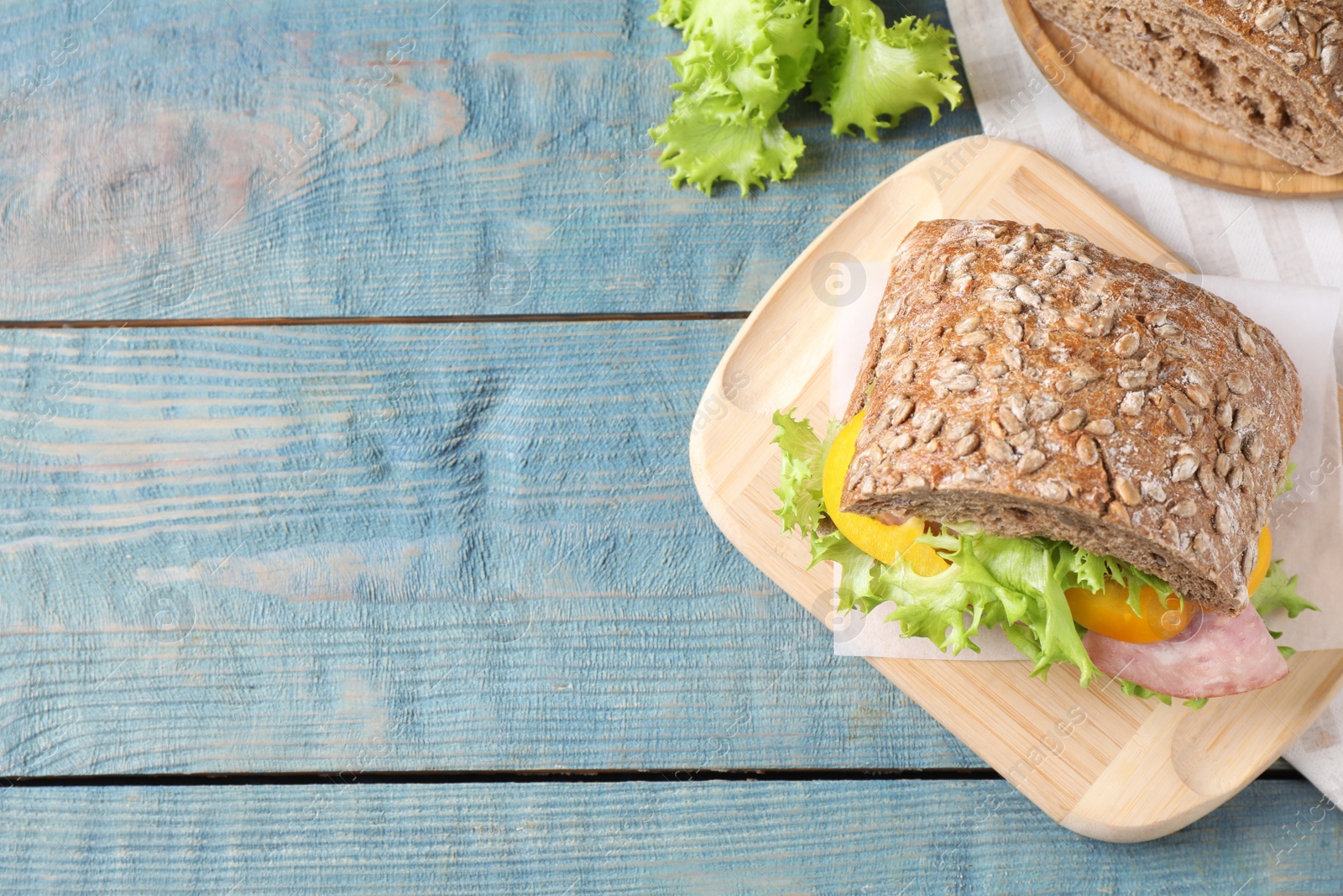 Photo of Tasty sandwich with ham on light blue wooden table, flat lay. Space for text