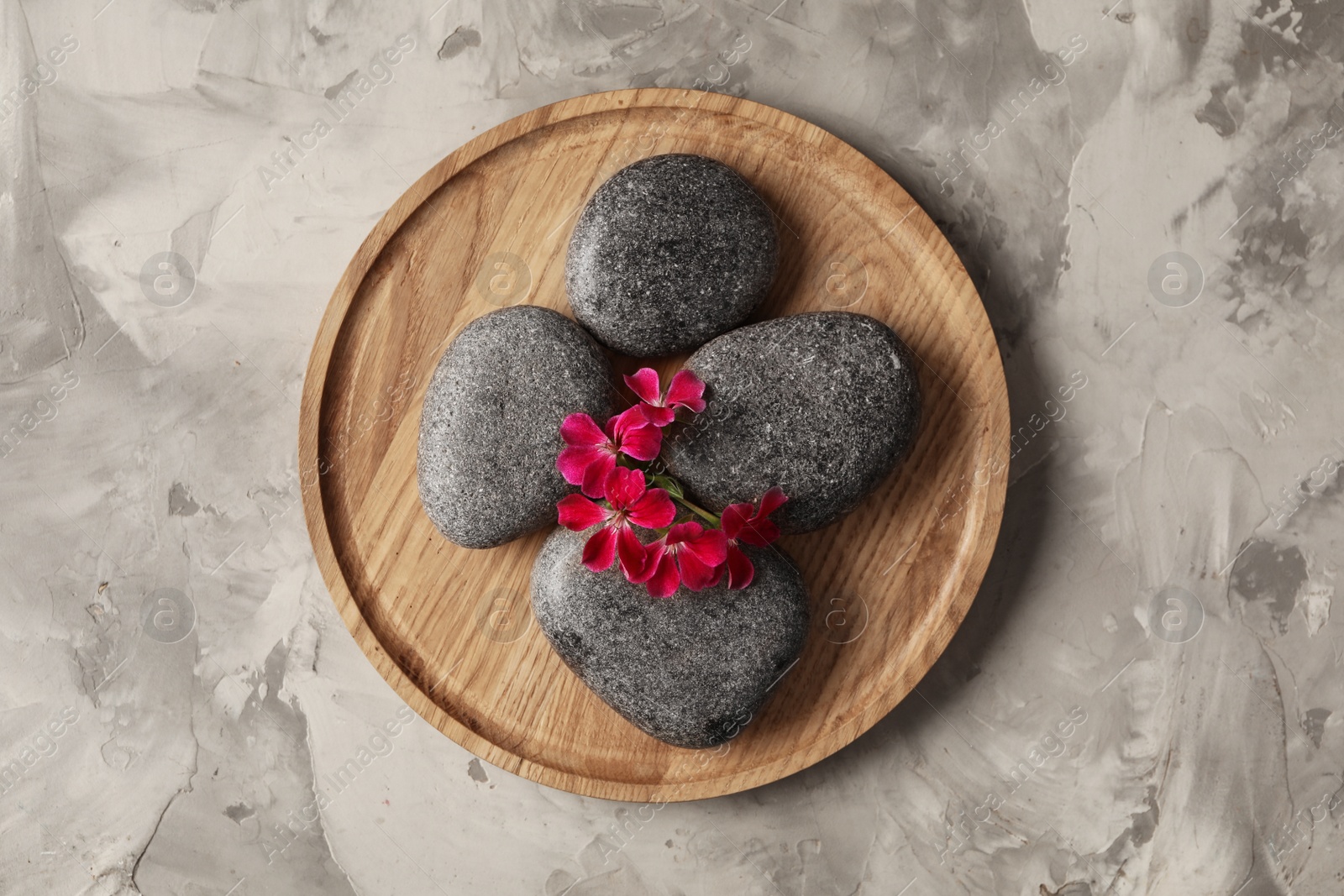 Photo of Spa stones and red flowers on grey table, top view