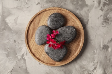 Photo of Spa stones and red flowers on grey table, top view