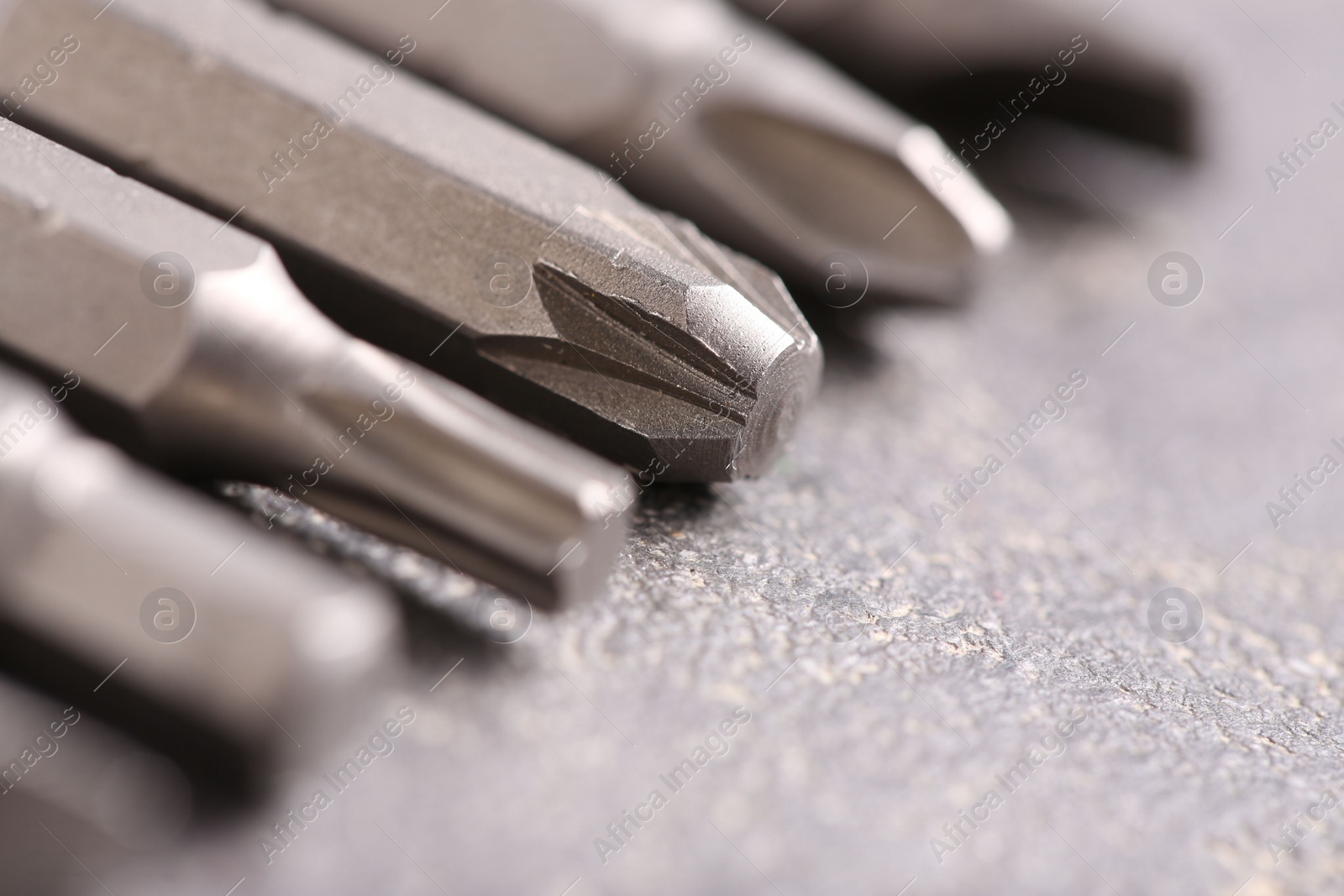 Photo of Different screwdriver bits on grey table, closeup