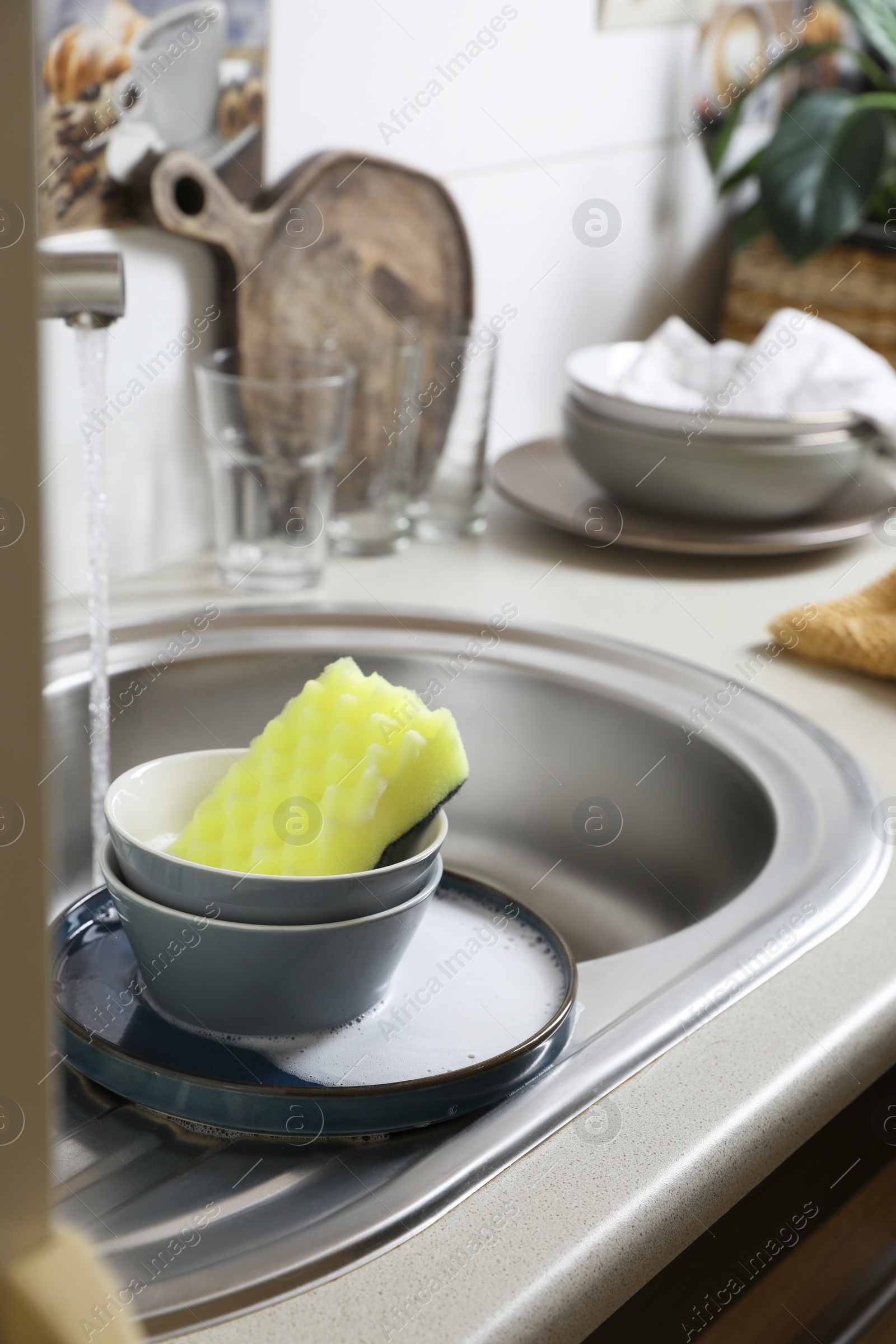 Photo of Bowls and sponge on kitchen sink. Washing dishes