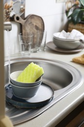 Photo of Bowls and sponge on kitchen sink. Washing dishes