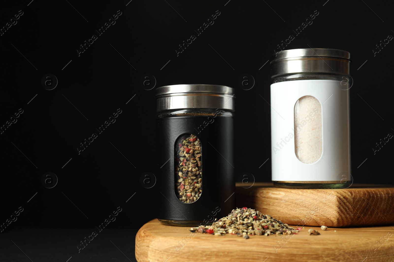 Photo of Salt and pepper shakers on table against black background. Space for text