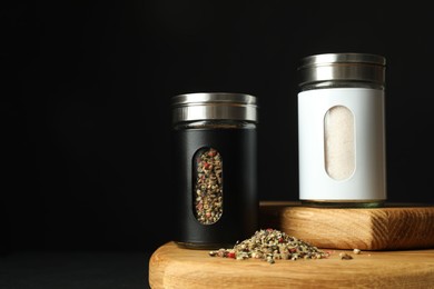 Salt and pepper shakers on table against black background. Space for text