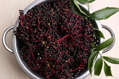 Photo of Tasty elderberries (Sambucus) on wooden table, top view