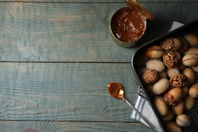 Photo of Freshly baked homemade walnut shaped cookies and boiled condensed milk on wooden table, flat lay. Space for text