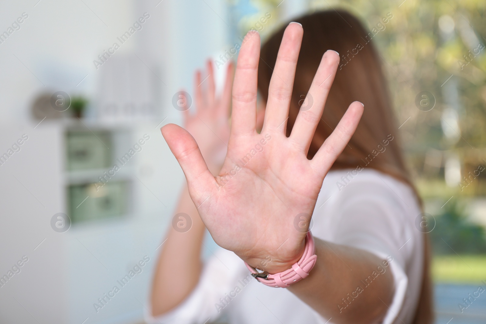 Photo of Woman showing stop gesture in office. Problem of sexual harassment at work