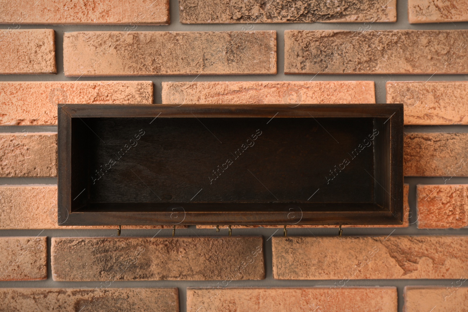 Photo of Empty wooden shelf with hanger for keys on brick wall