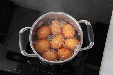 Chicken eggs boiling in pot on electric stove, top view