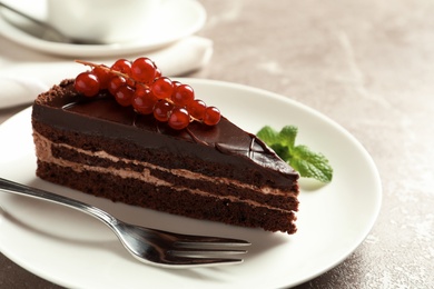 Photo of Plate with slice of tasty chocolate cake and fork on table