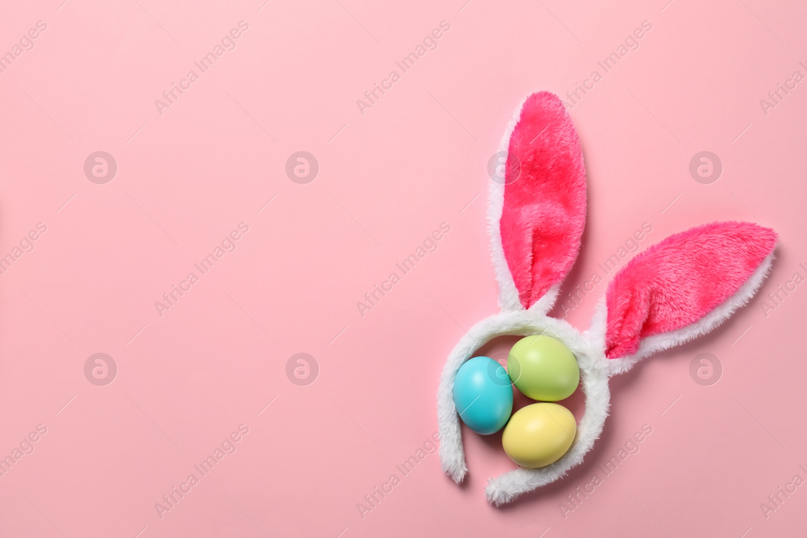 Photo of Funny headband with Easter bunny ears and dyed eggs on color background, flat lay. Space for text