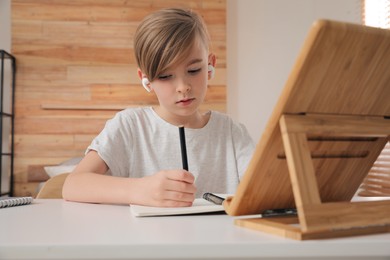 Boy in earphones doing homework at table indoors