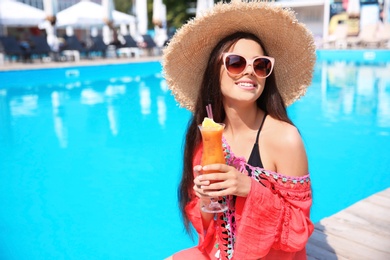 Photo of Beautiful young woman with cocktail near outdoor swimming pool