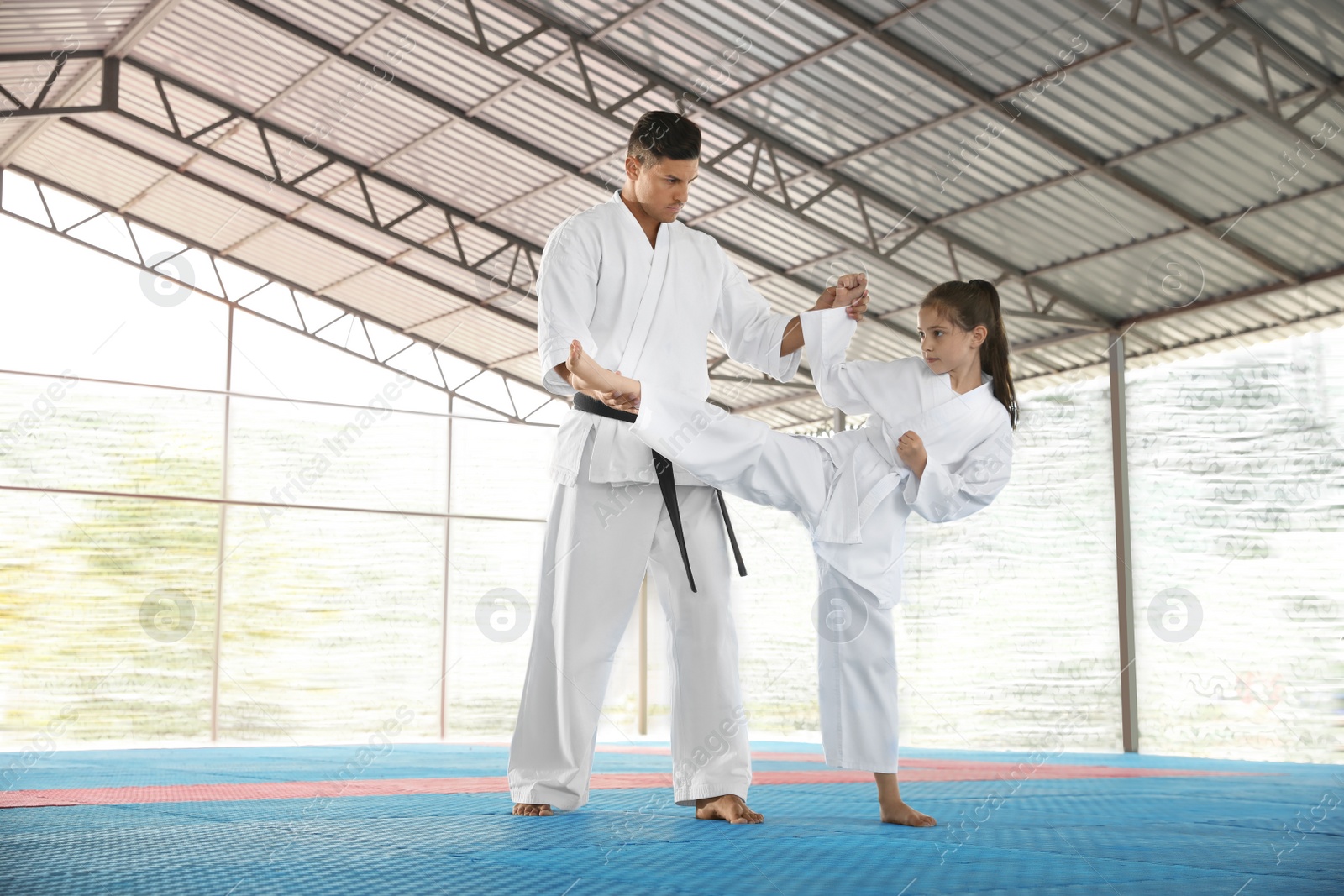 Photo of Girl practicing karate with coach on tatami outdoors