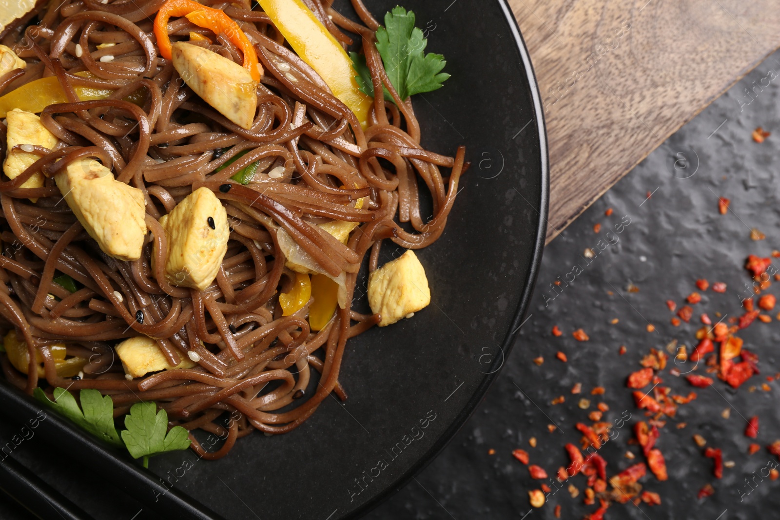 Photo of Stir-fry. Tasty noodles with vegetables and meat on dark table, top view. Space for text