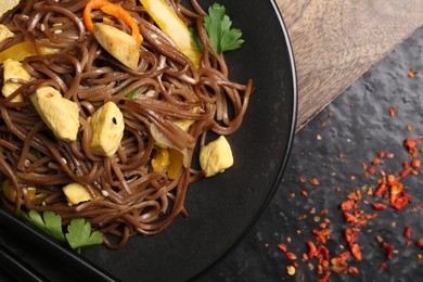 Photo of Stir-fry. Tasty noodles with vegetables and meat on dark table, top view. Space for text