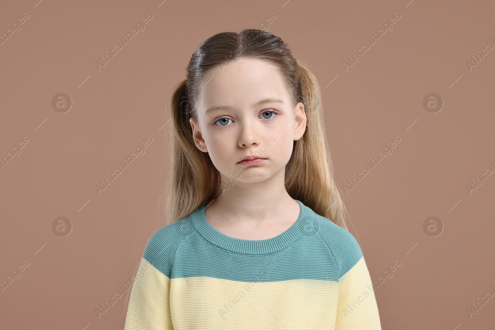 Photo of Portrait of sad girl on light brown background