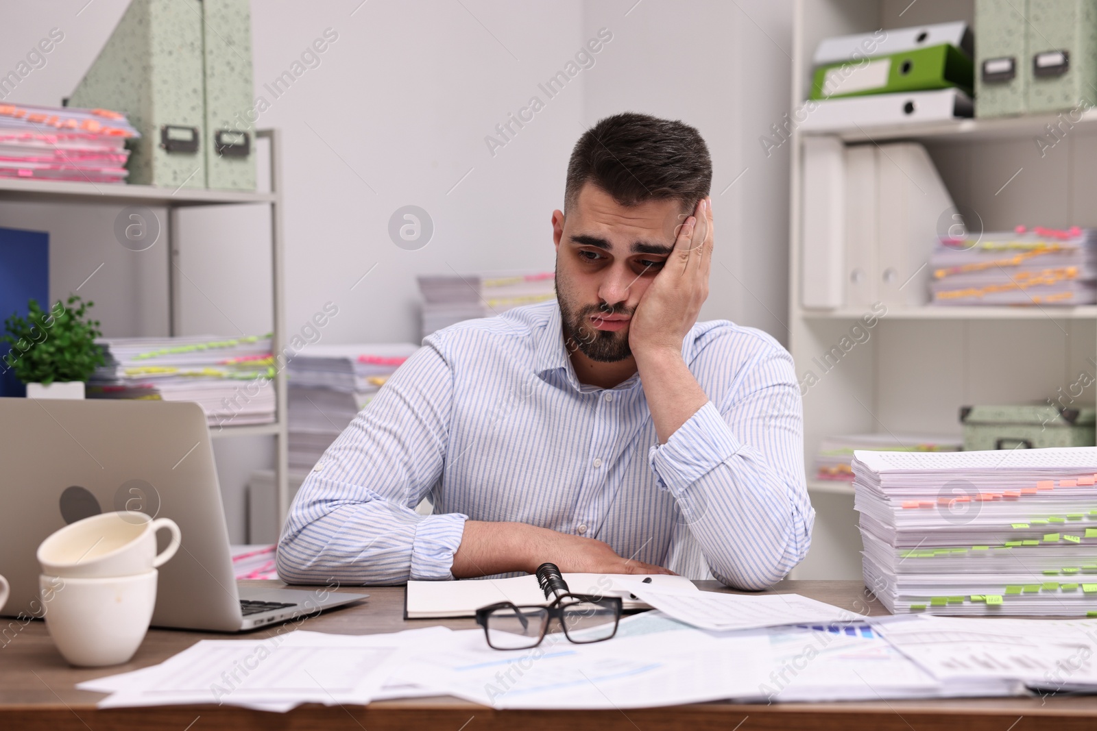 Photo of Overwhelmed man sitting at table in office