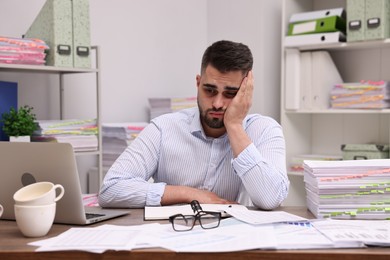 Overwhelmed man sitting at table in office