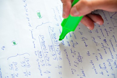 Photo of Student highlighting with green marker mathematical calculations, closeup