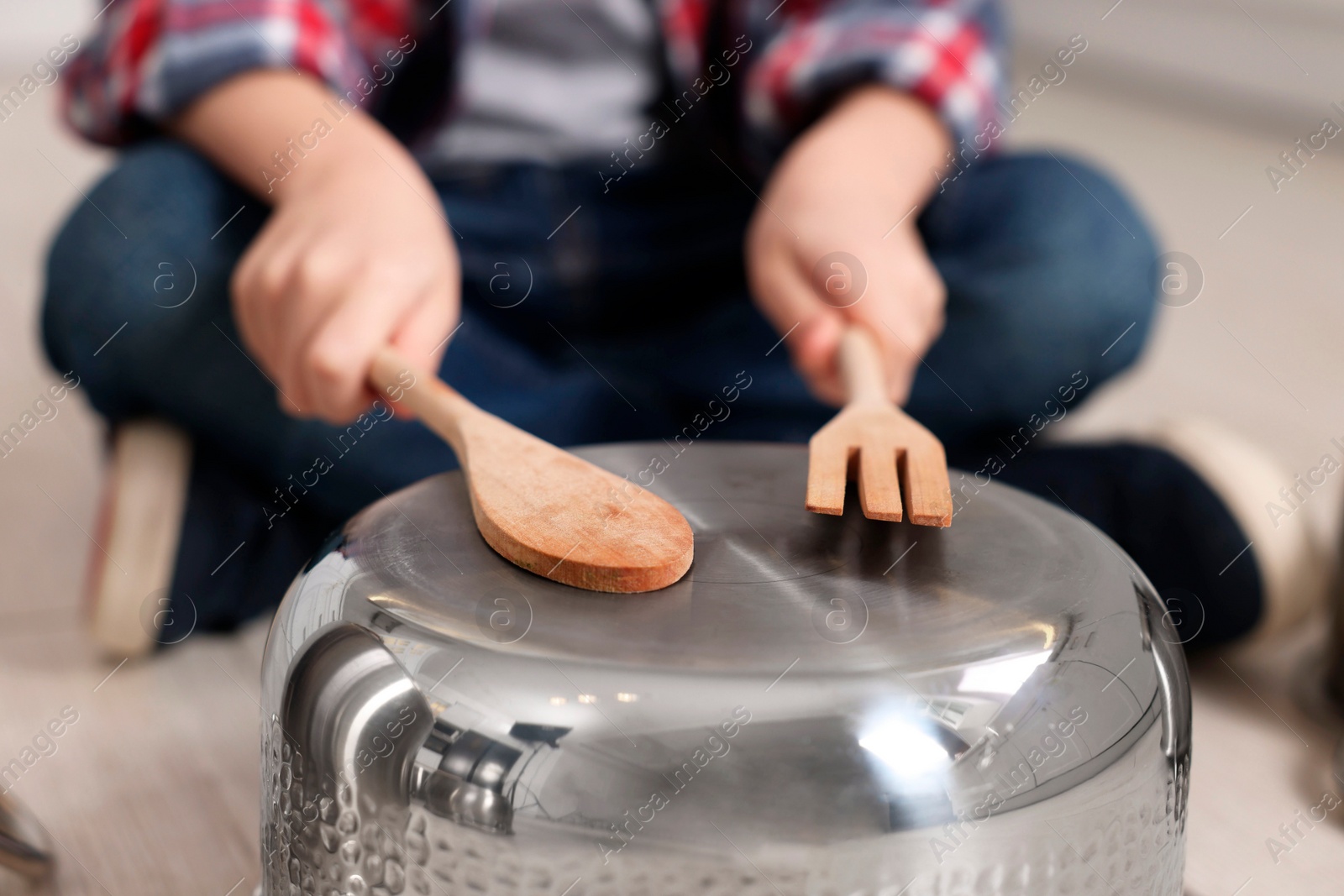 Photo of Little boy pretending to play drum on pot indoors, closeup