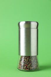 Photo of One pepper shaker on green background, closeup