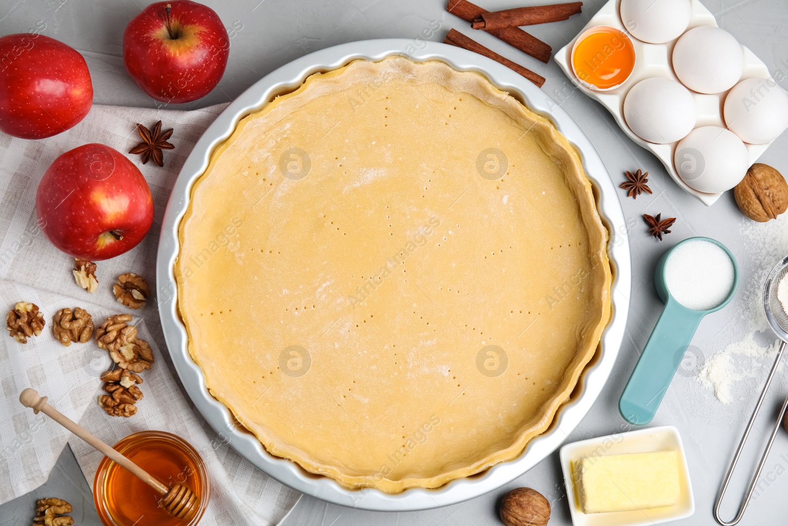 Photo of Raw dough and ingredients for traditional English apple pie on light grey table, flat lay