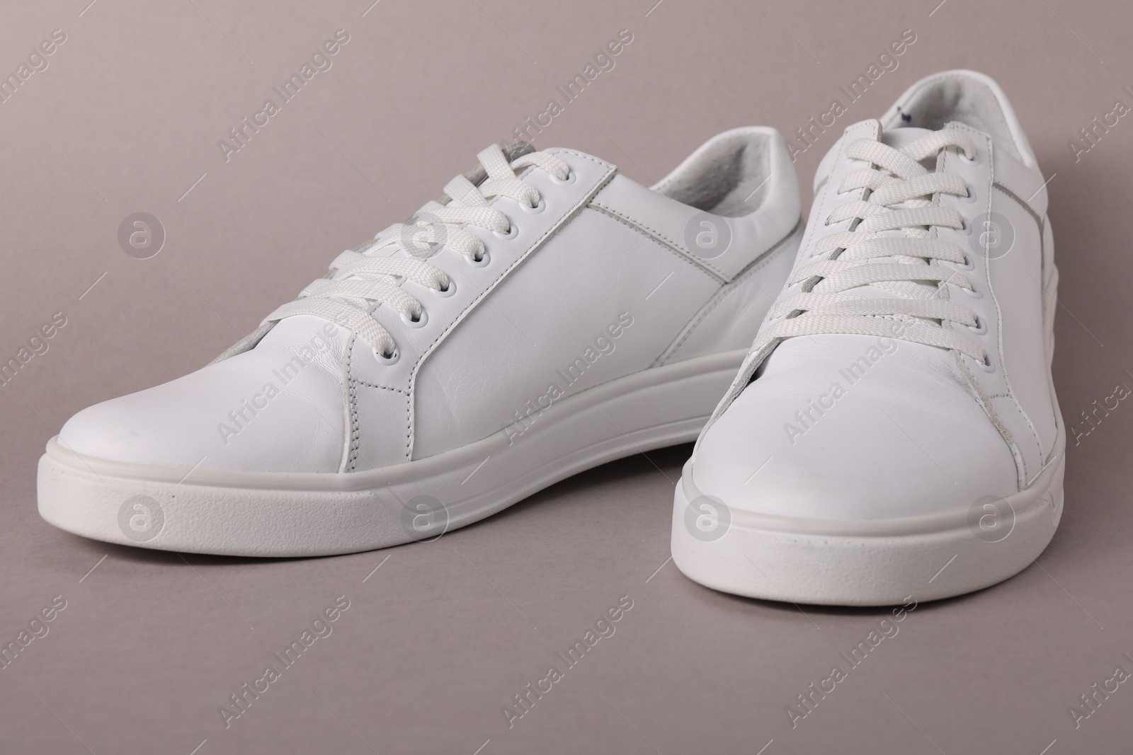 Photo of Pair of stylish white sneakers on grey background, closeup