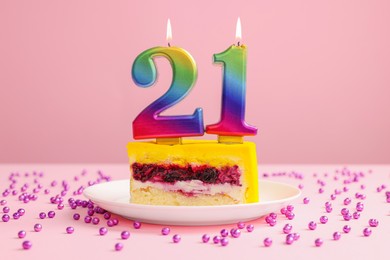 Photo of Coming of age party - 21st birthday. Delicious cake with number shaped candles on pink background