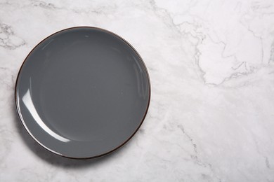 Photo of One grey ceramic plate on white marble table, top view. Space for text