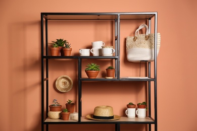 Photo of Stylish shelving unit with decorative elements near color wall. Interior design