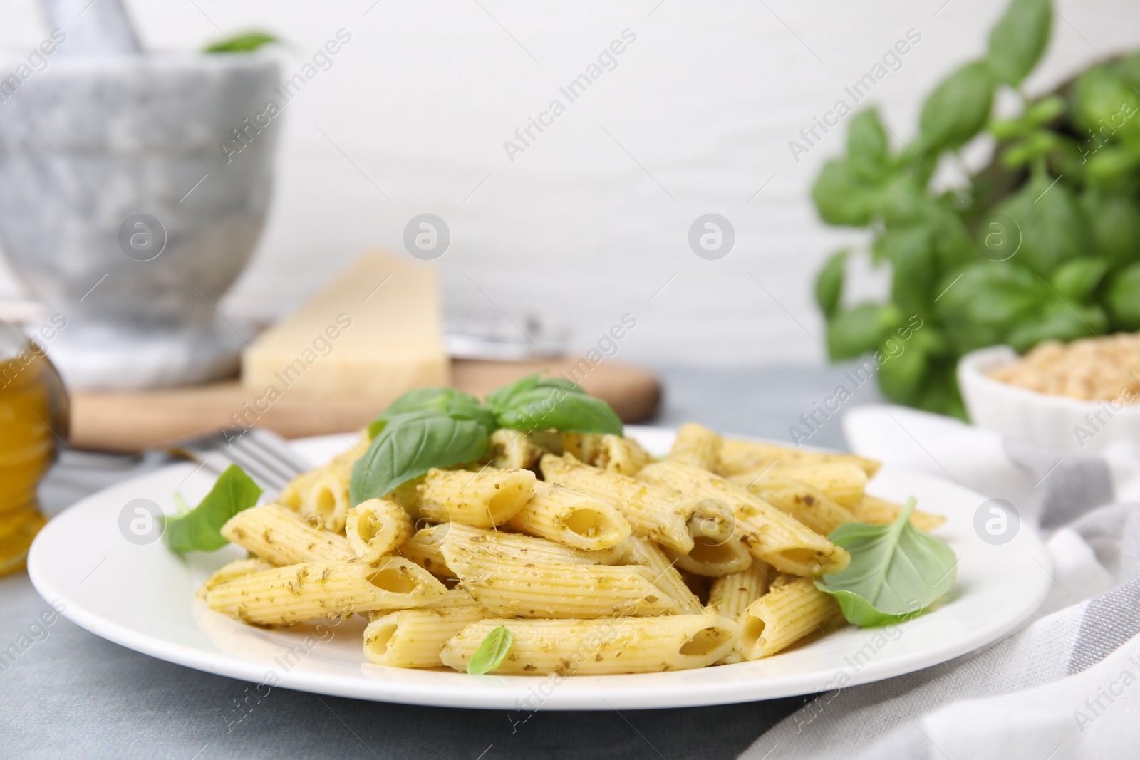 Photo of Delicious pasta with pesto sauce and basil on light grey table, closeup. Space for text