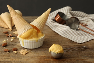 Delicious yellow ice cream and wafer cones on wooden table