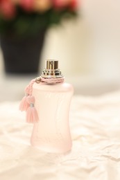 Photo of Bottle of perfume on crumpled paper against blurred background