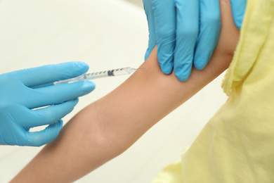 Photo of Doctor vaccinating little child in clinic, closeup