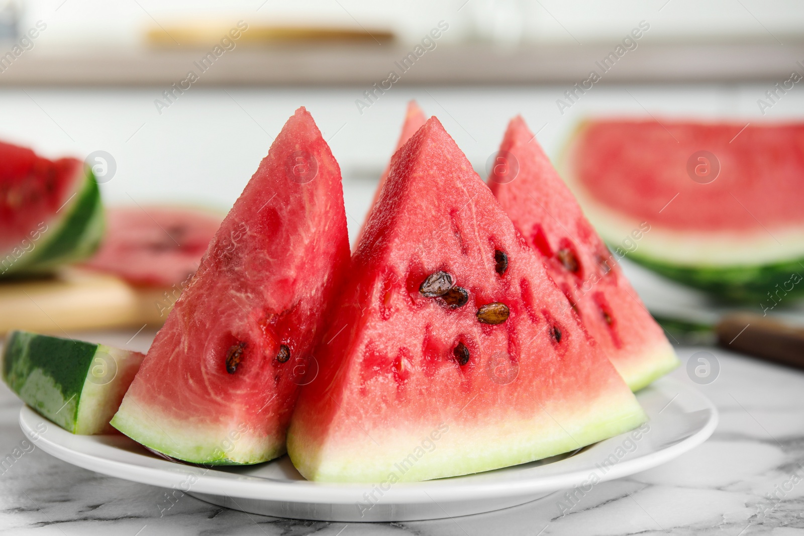 Photo of Yummy watermelon slices on white marble table in kitchen, closeup