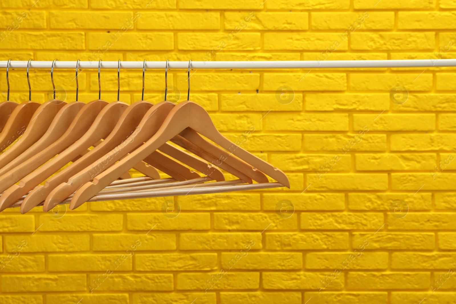 Photo of Wardrobe rack with many hangers near yellow brick wall