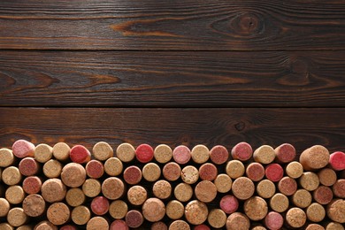 Photo of Many corks of wine bottles on wooden table, top view. Space for text