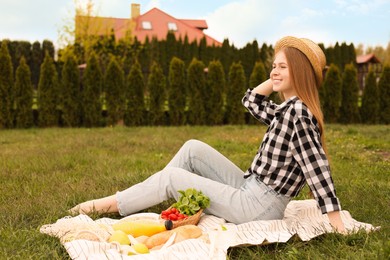 Happy girl having picnic on green grass in park