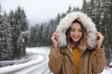 Photo of Young woman in warm clothes outdoors, space for text. Winter vacation