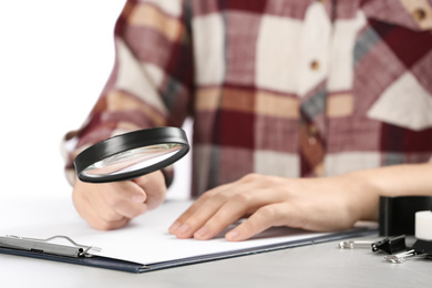 Photo of Woman using magnifying glass at table, closeup